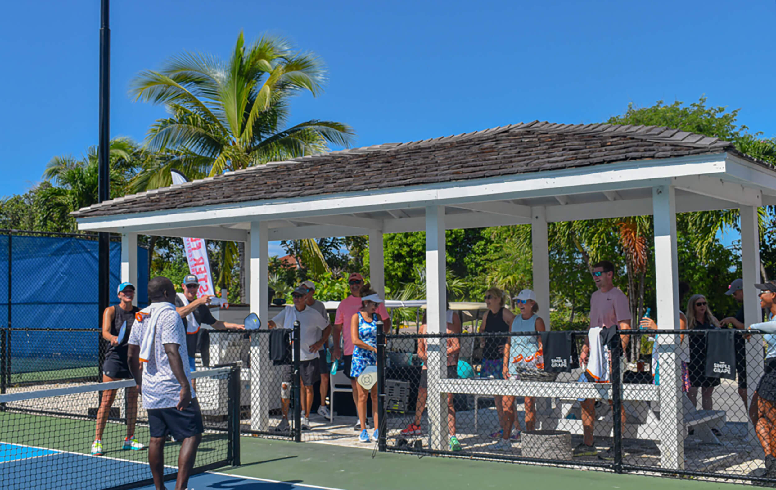 People at a pickle ball court chatting and enjoying club lifestyle at The Abaco Club