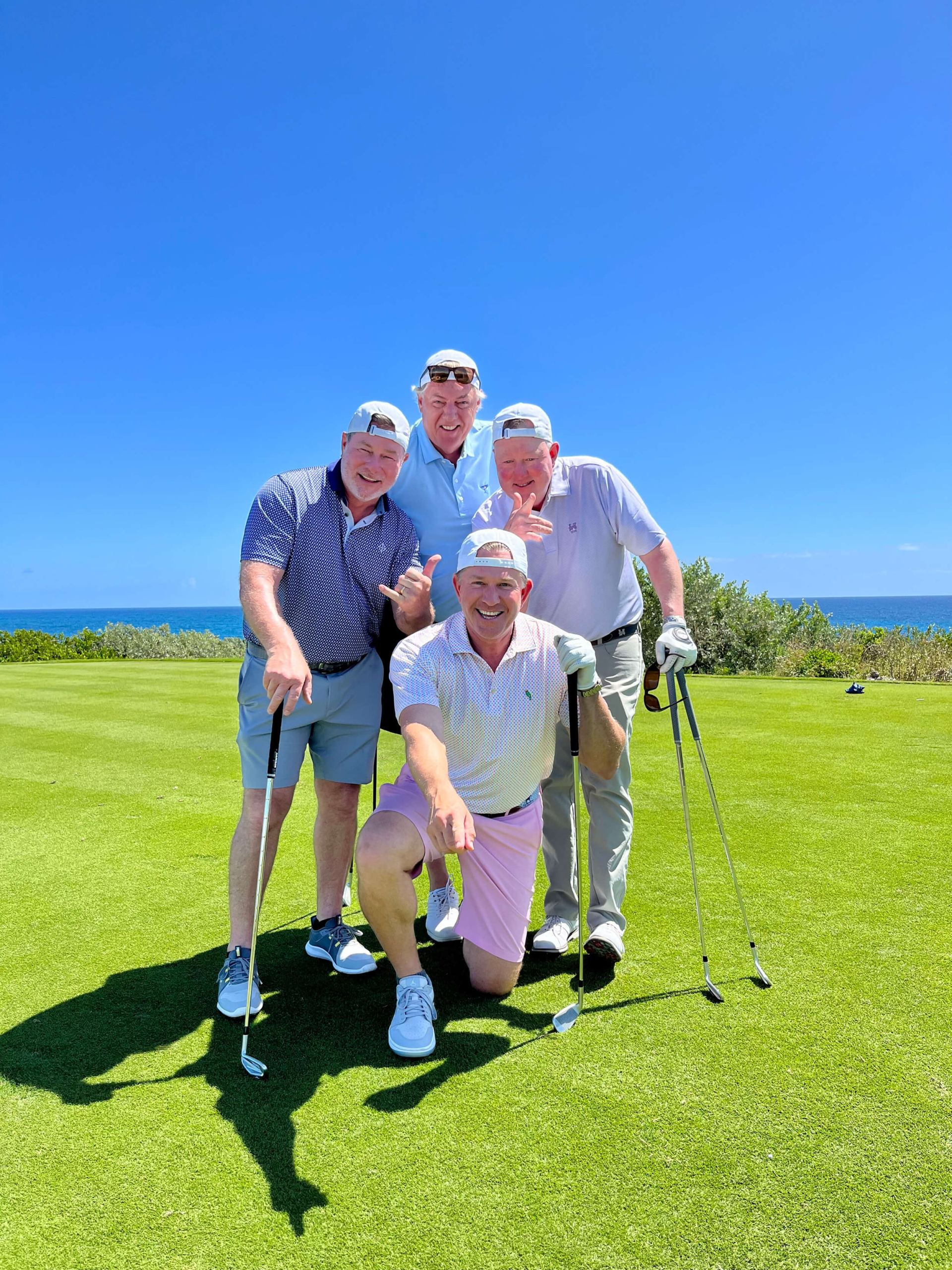 Group of golfers sharing a joyful moment on The Abaco Club golf course with scenic coastal views