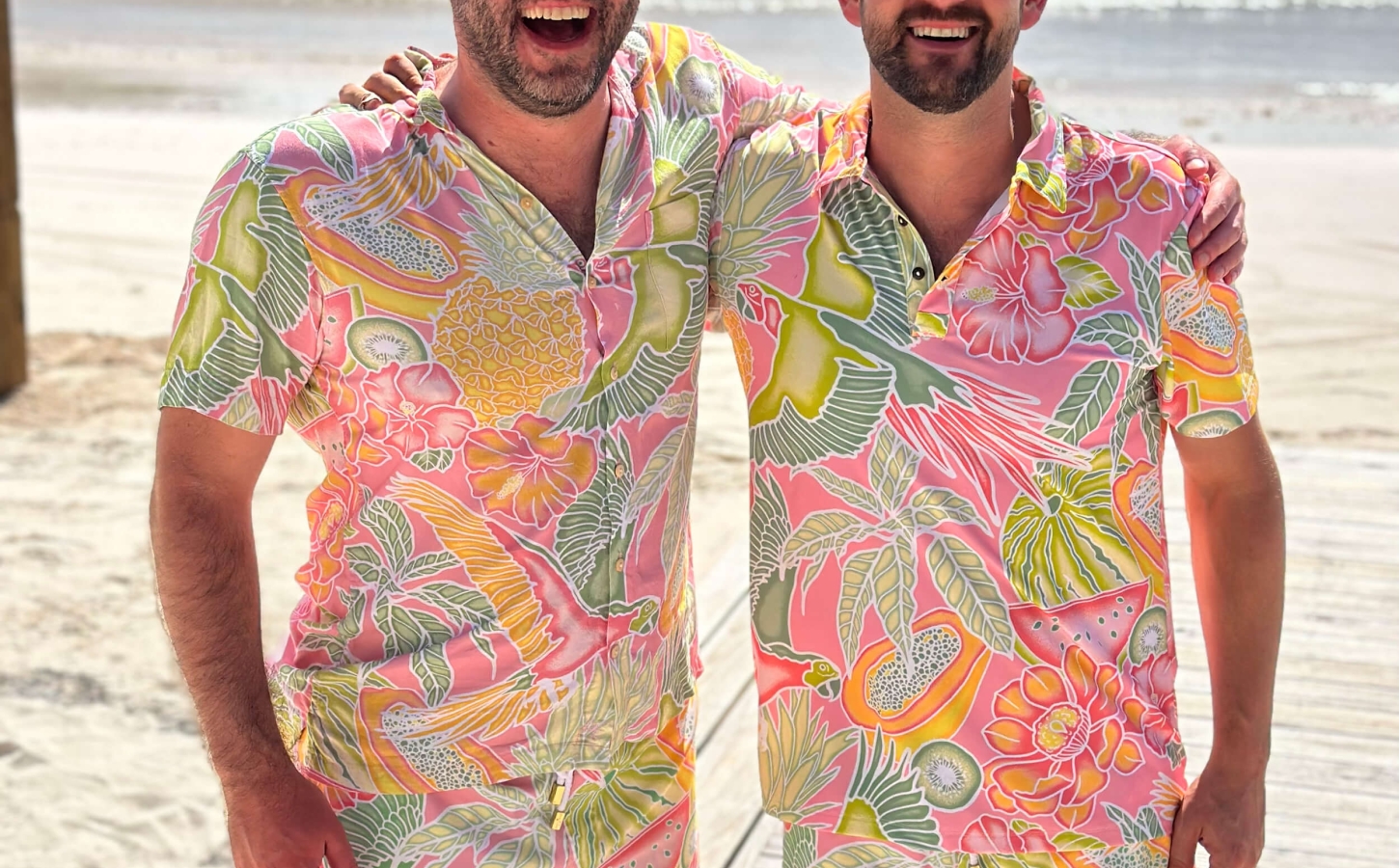 Two Abaco Club members posing and smiling with matching tropical clothes