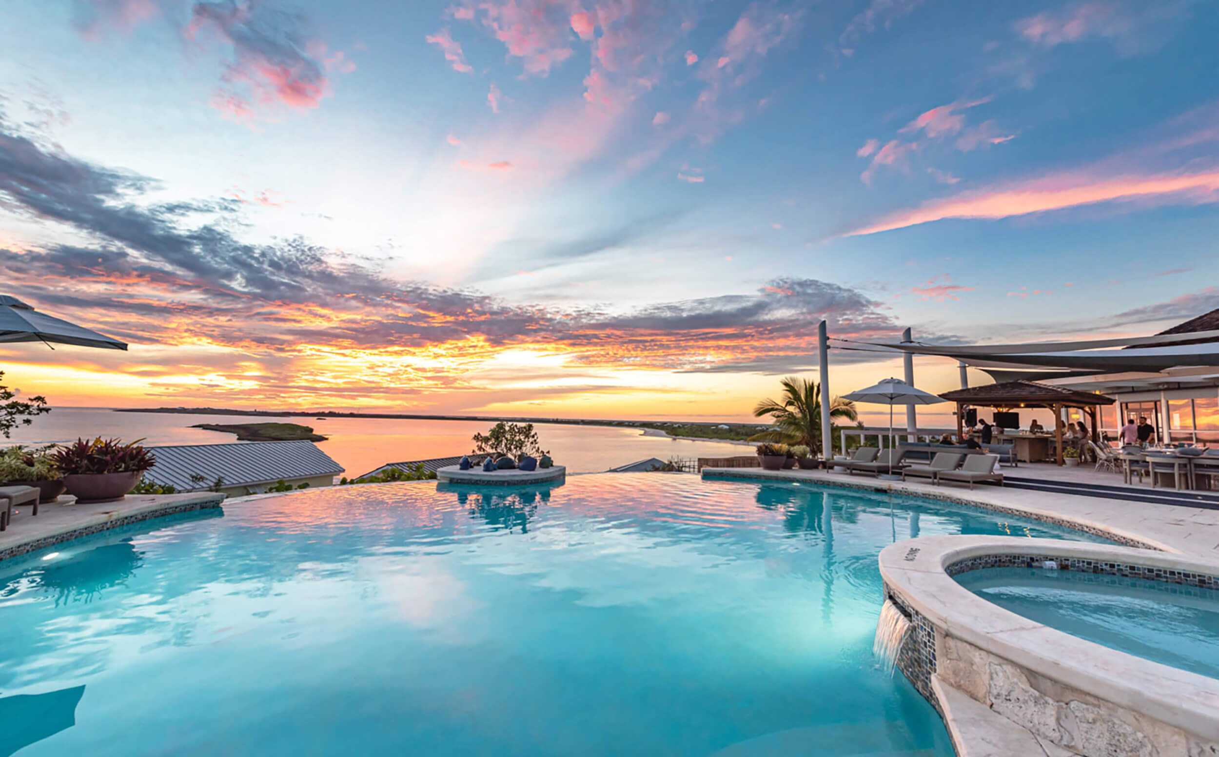 Sunset view at The Abaco Club showcasing a luxurious pool reflecting vibrant skies, embodying coastal living and club lifestyle