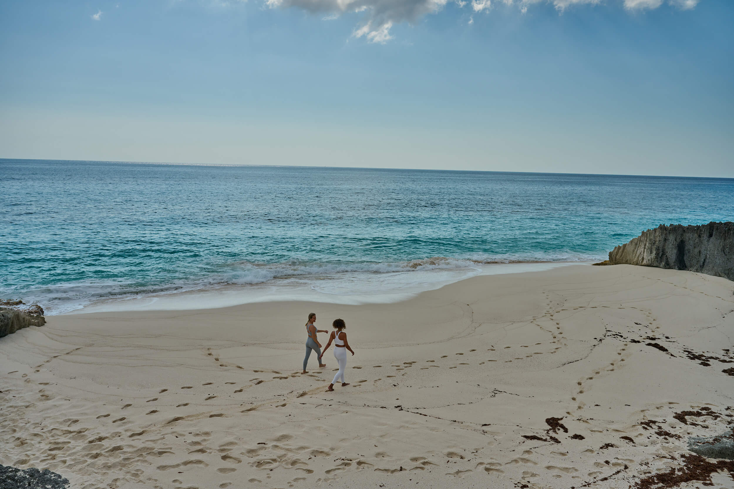 Two women walking on the beach of The Abaco Club