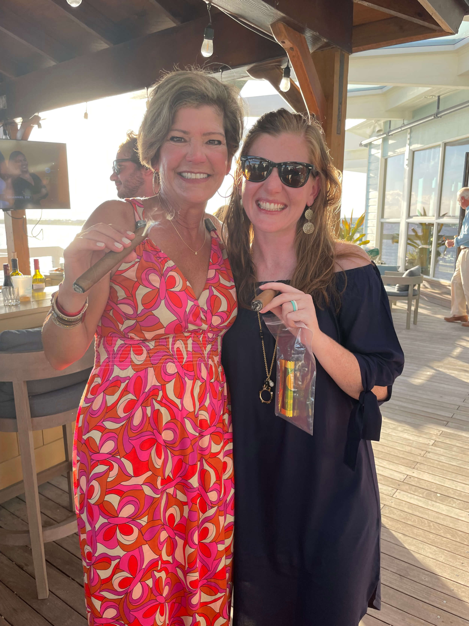 Smiling guests holding cigars at an event, representing the sophisticated club lifestyle and coastal living at The Abaco Club.