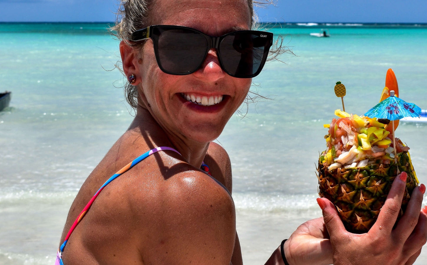 A woman enjoying a cocktail at the pristine beach of The Abaco Club