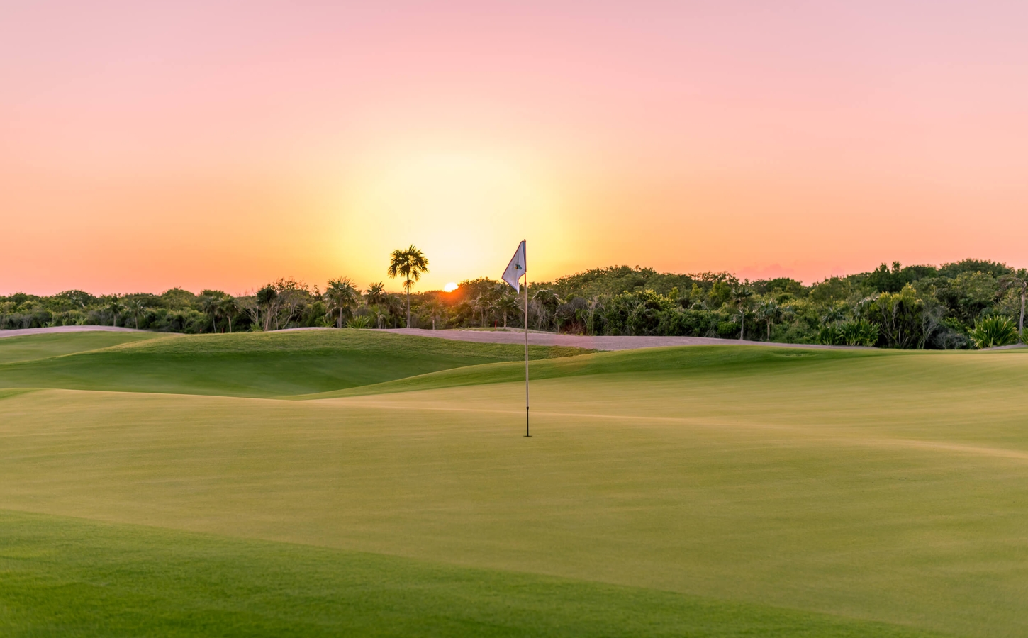 The Abaco Club 8th Green with a coast sunset on the background