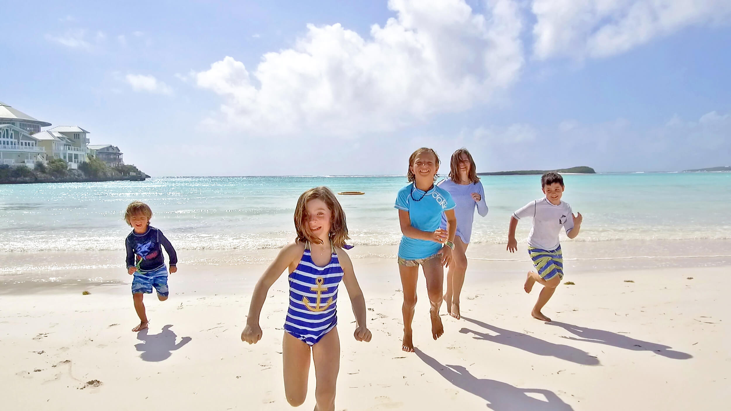 Kids running along The Abaco Club beach