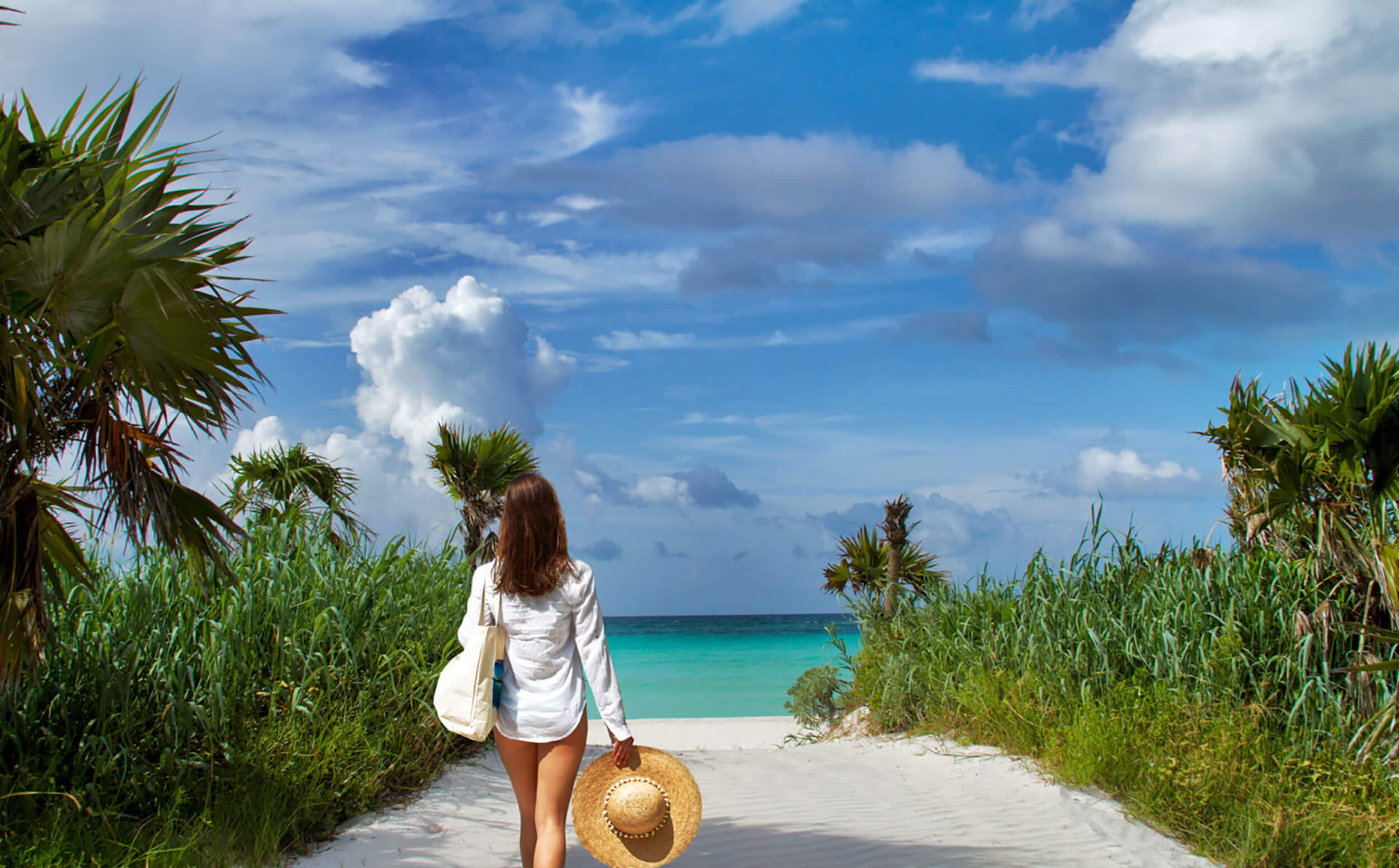 Woman walking towards the beach at The Abaco Club, epitomizing the serene coastal lifestyle in The Bahamas.