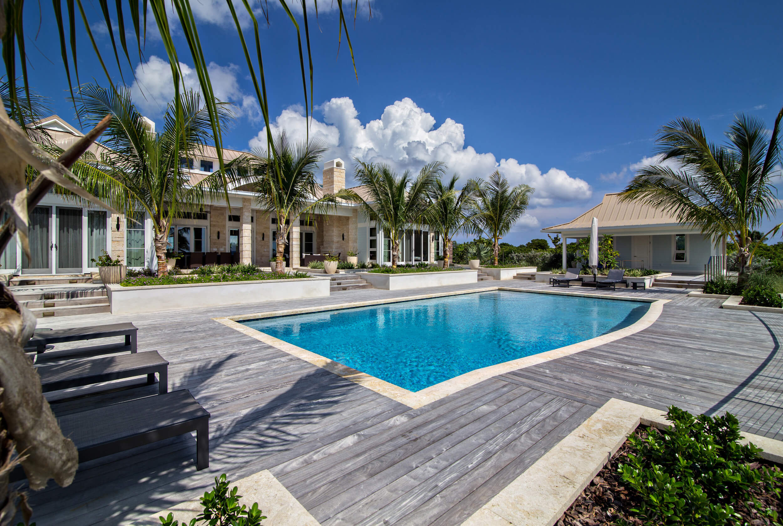 Inviting poolside view at The Abaco Club estate, framed by elegant architecture and palm trees, embodying the serene coastal living in The Bahamas