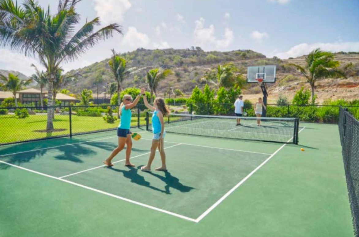 A friendly doubles match taking place at The Abaco Club's tennis courts, reflecting the active and social club lifestyle