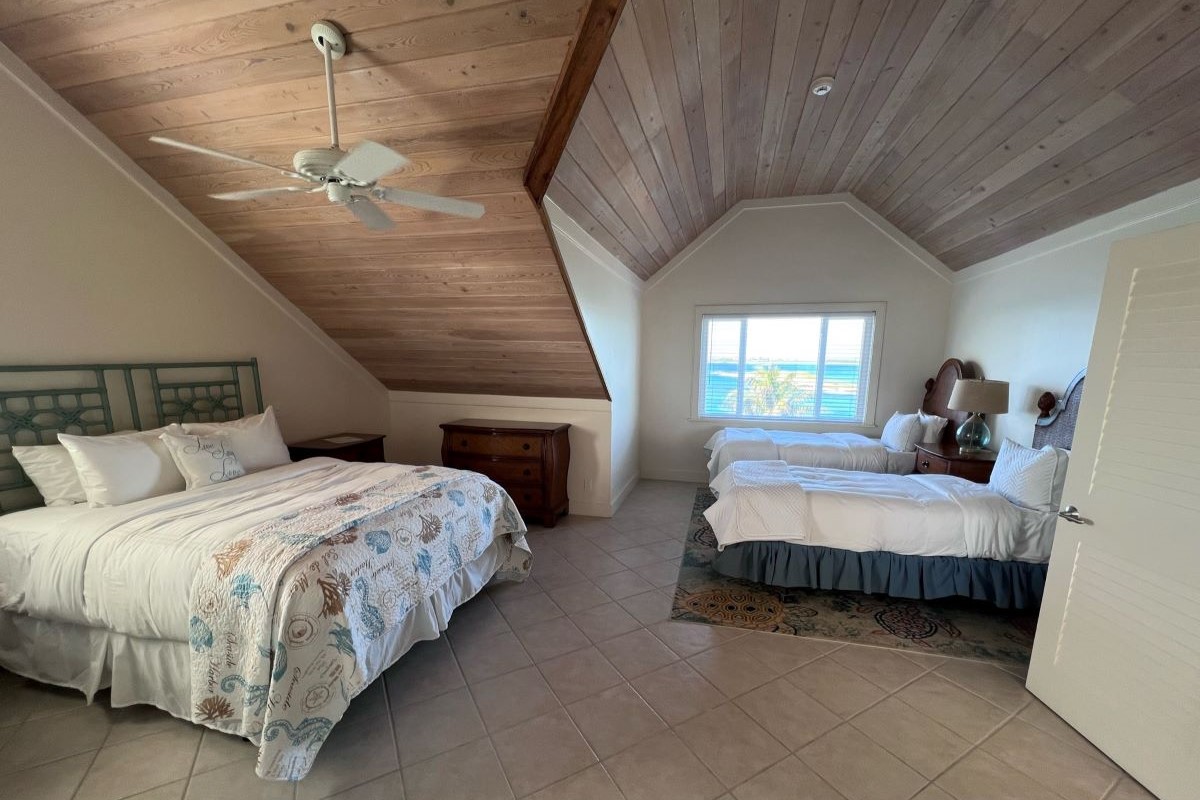 An Abaco Club property with an elegant and spacious bedroom with queen bed and two twin beds and a ocean view