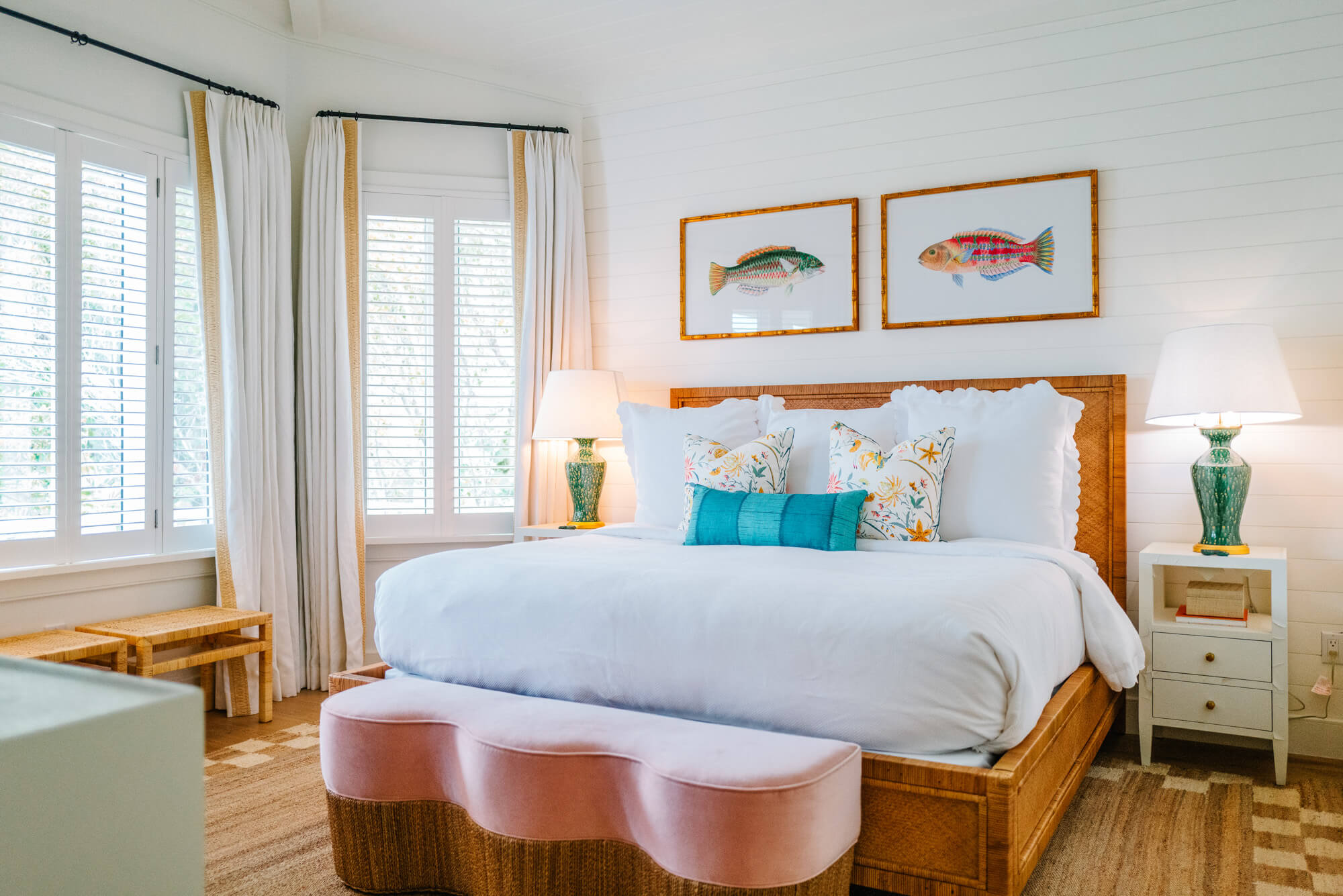 Bright coastal-style bedroom with white shiplap walls, a wooden bed frame, and two framed fish prints above the headboard