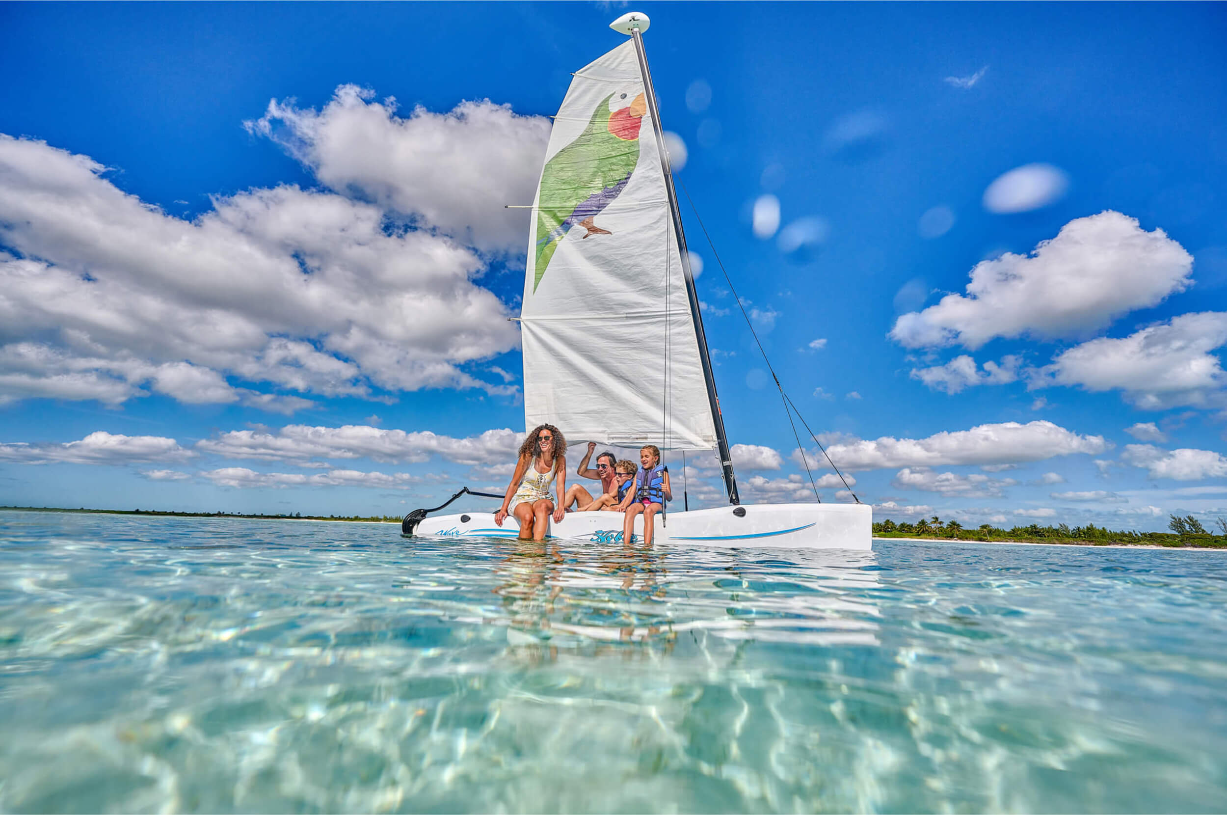 Family enjoying a sailboat ride in the crystal-clear waters near The Abaco Club, capturing the essence of adventure in Bahamian coastal living.