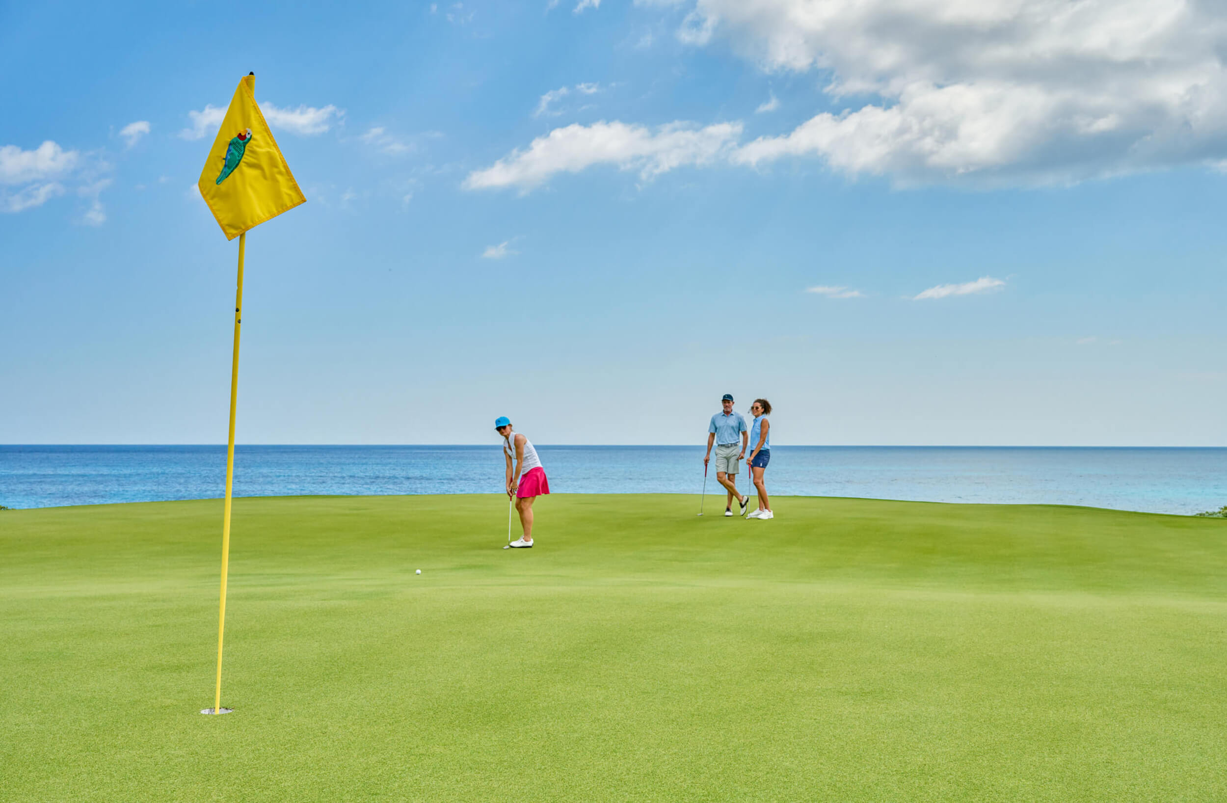 Golfers at The Abaco Club enjoying a sunny day on the greens, with the background of the Bahamian sea