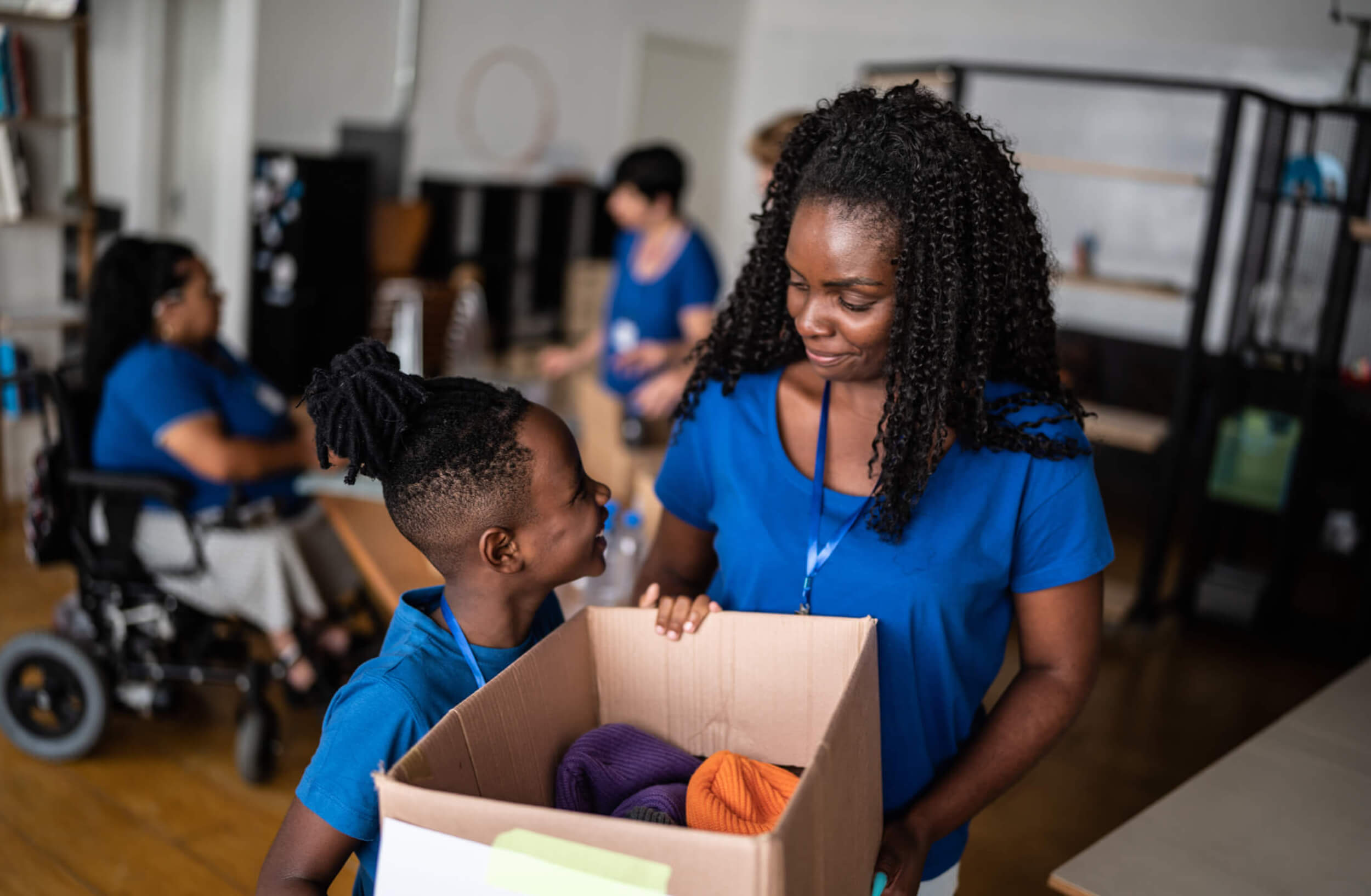 Volunteers from The Abaco Club participating in a philanthropic event, a woman and young boy in matching blue shirts share a moment while organizing donated items, demonstrating the club's commitment to supporting communities in the Bahamas